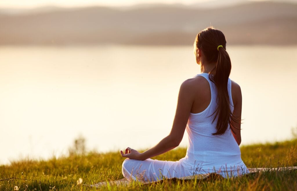 ženska ki meditira ob vodi