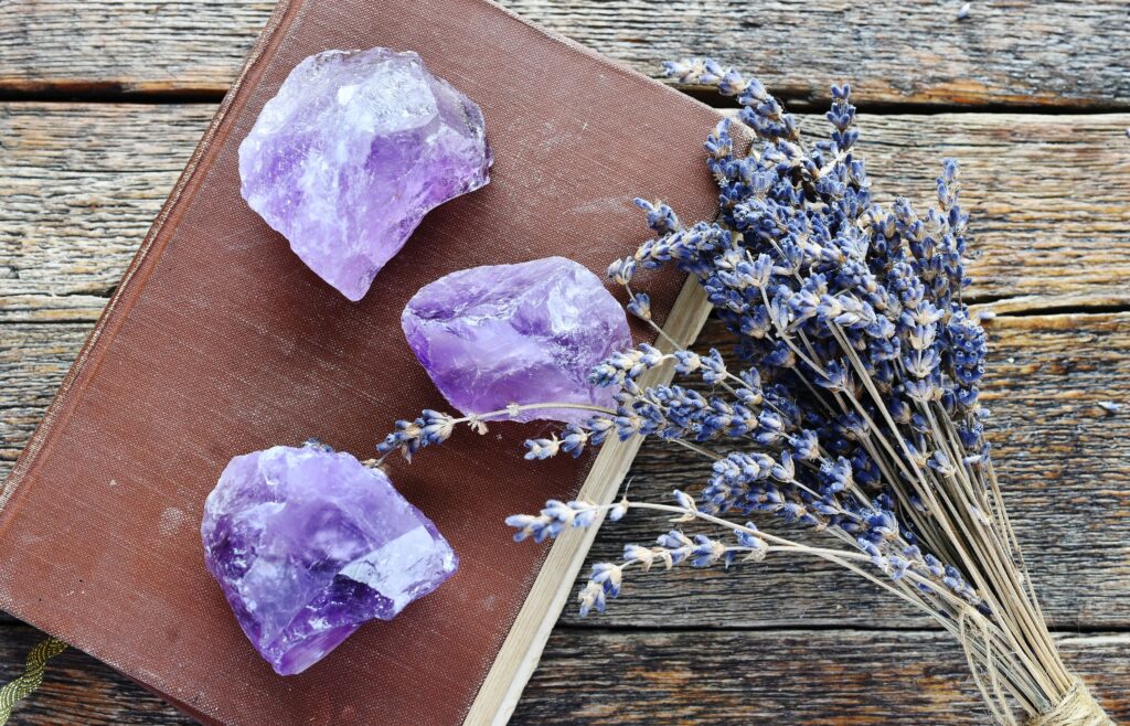 trije kristali ametista na mizi s sivko